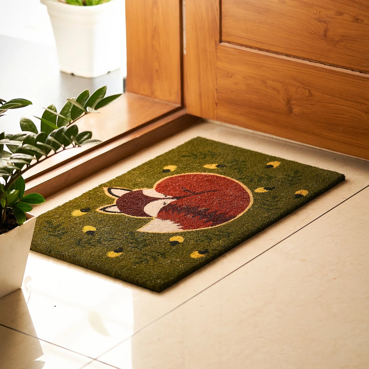 Doormat with a fox design on a tiled floor next to a wooden door.