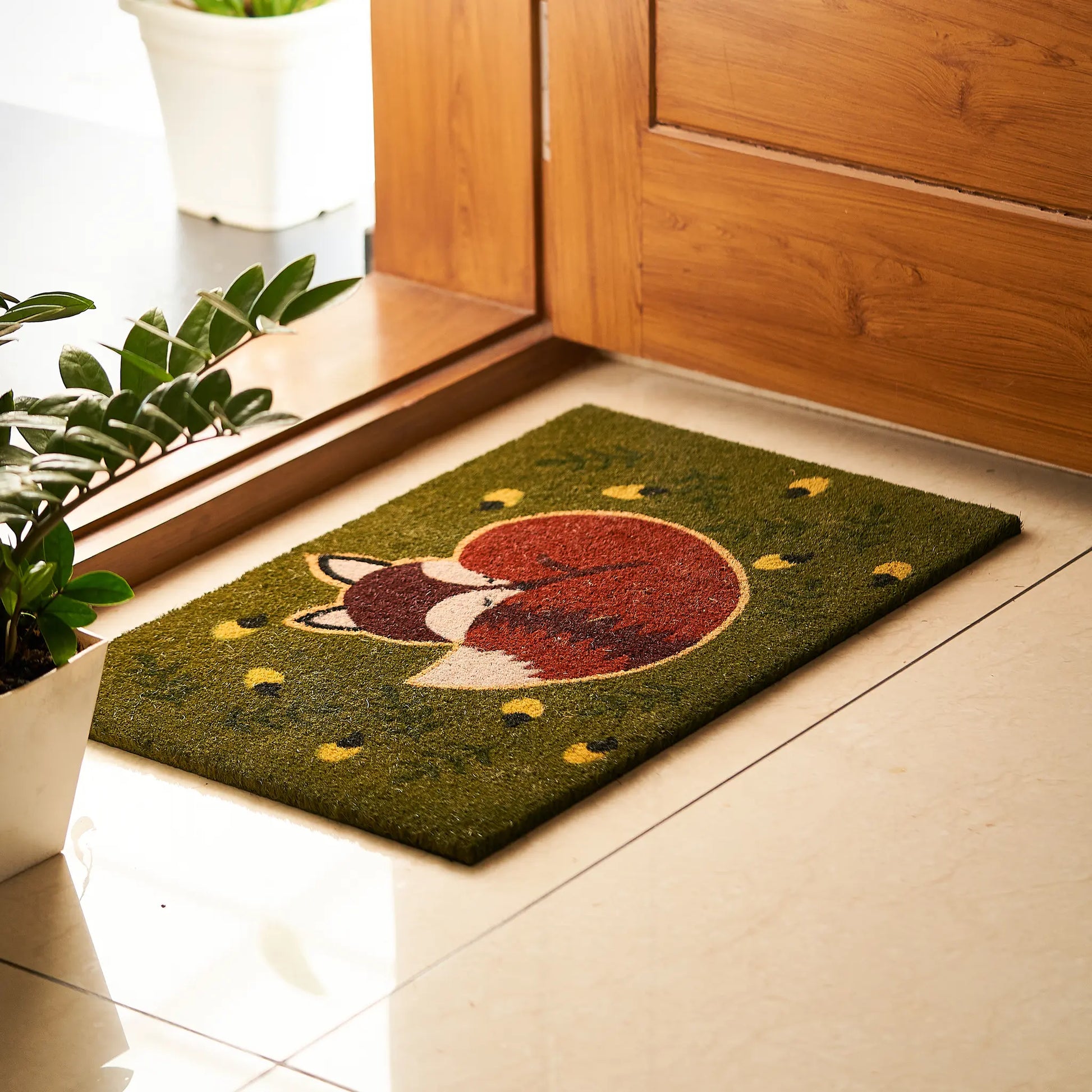 Doormat with a fox design on a tiled floor next to a wooden door.