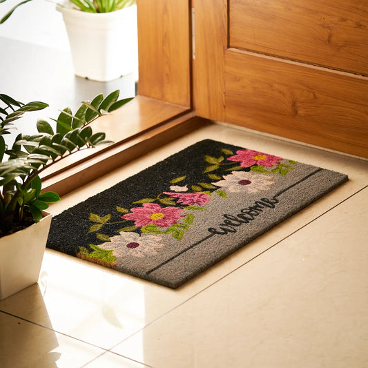Decorative doormat with floral design and 'Welcome' text on a tiled floor.