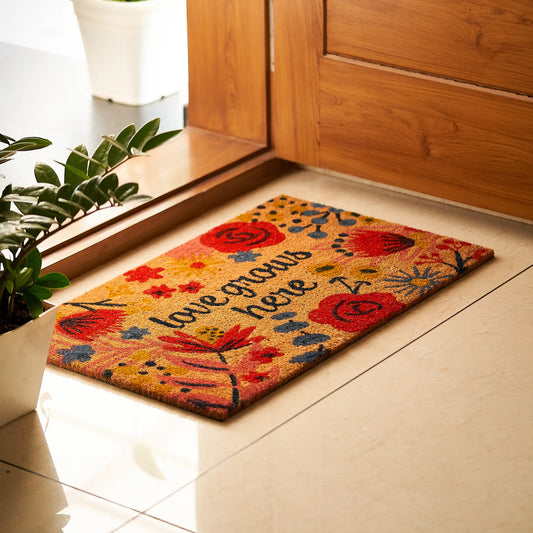 Decorative doormat with floral design and text on a tiled floor.