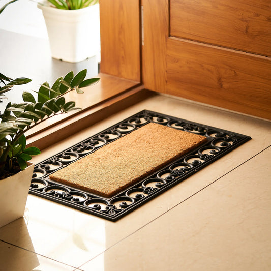 Doormat with decorative border on a tiled floor next to a wooden door.